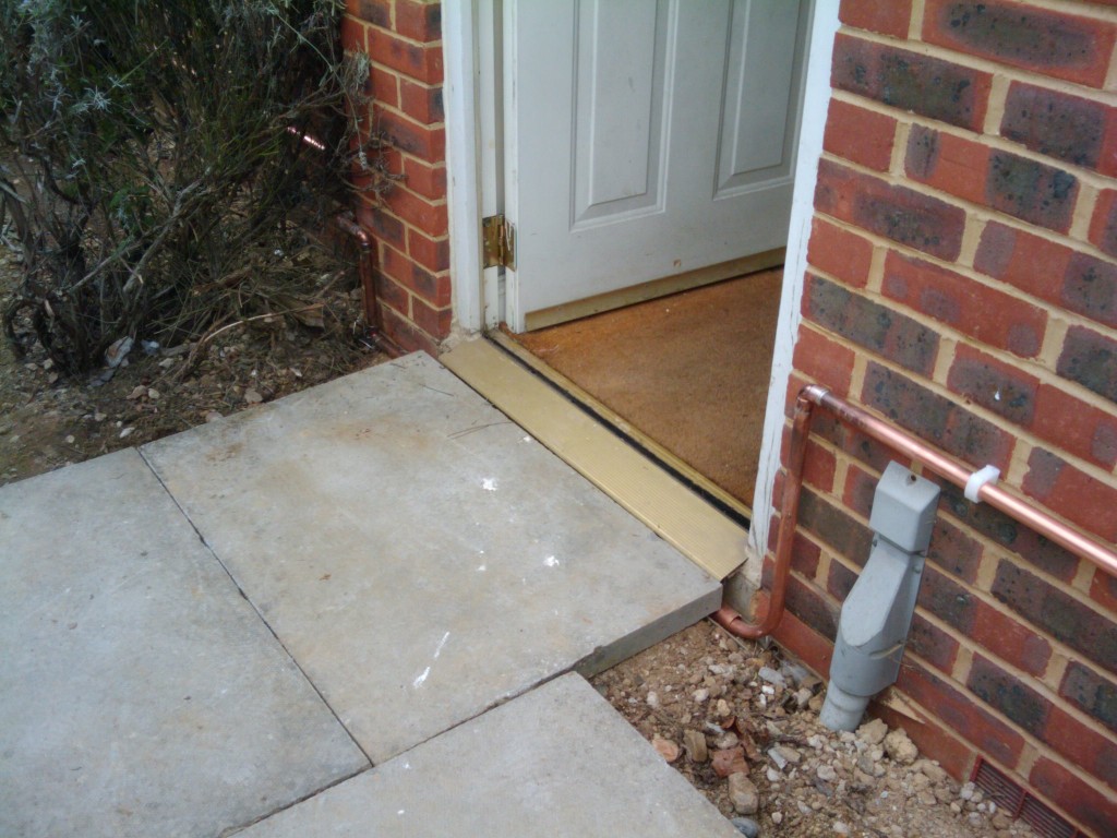 Copper pipes running under the front door threshold - need to de-wobble the paving stone though